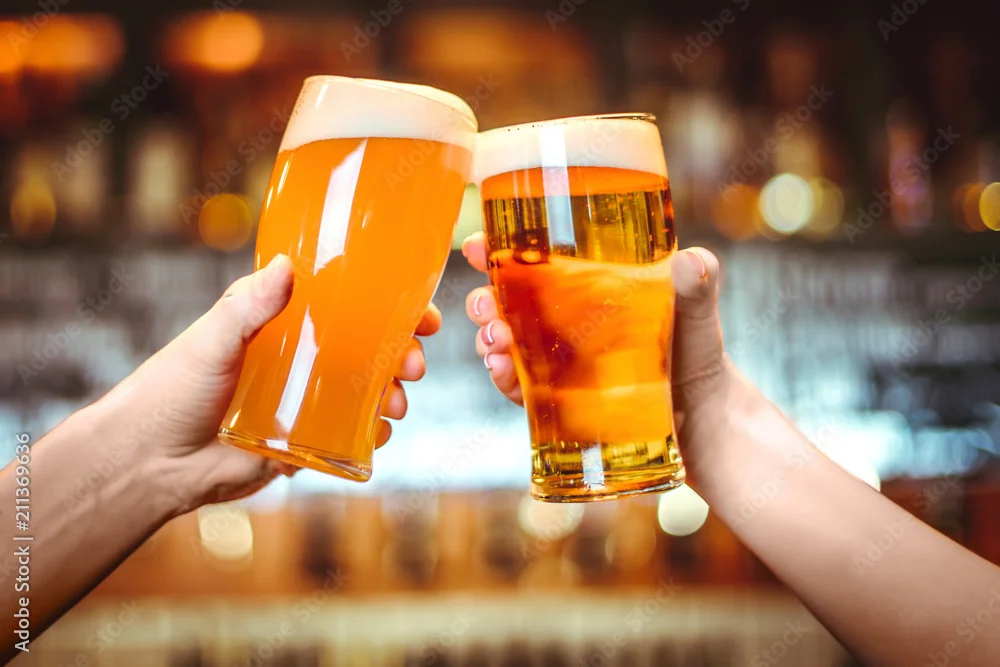 Cheers with two glasses of craft beer in a lively bar setting