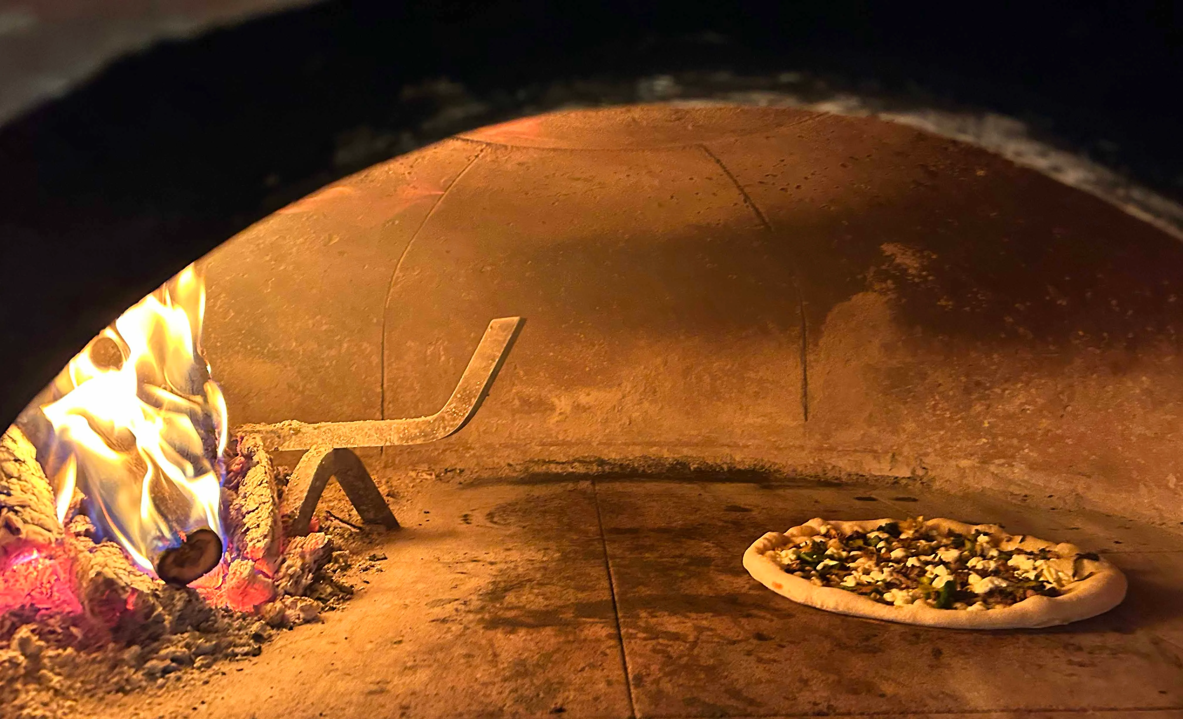 Wood-fired pizza baking in a traditional oven