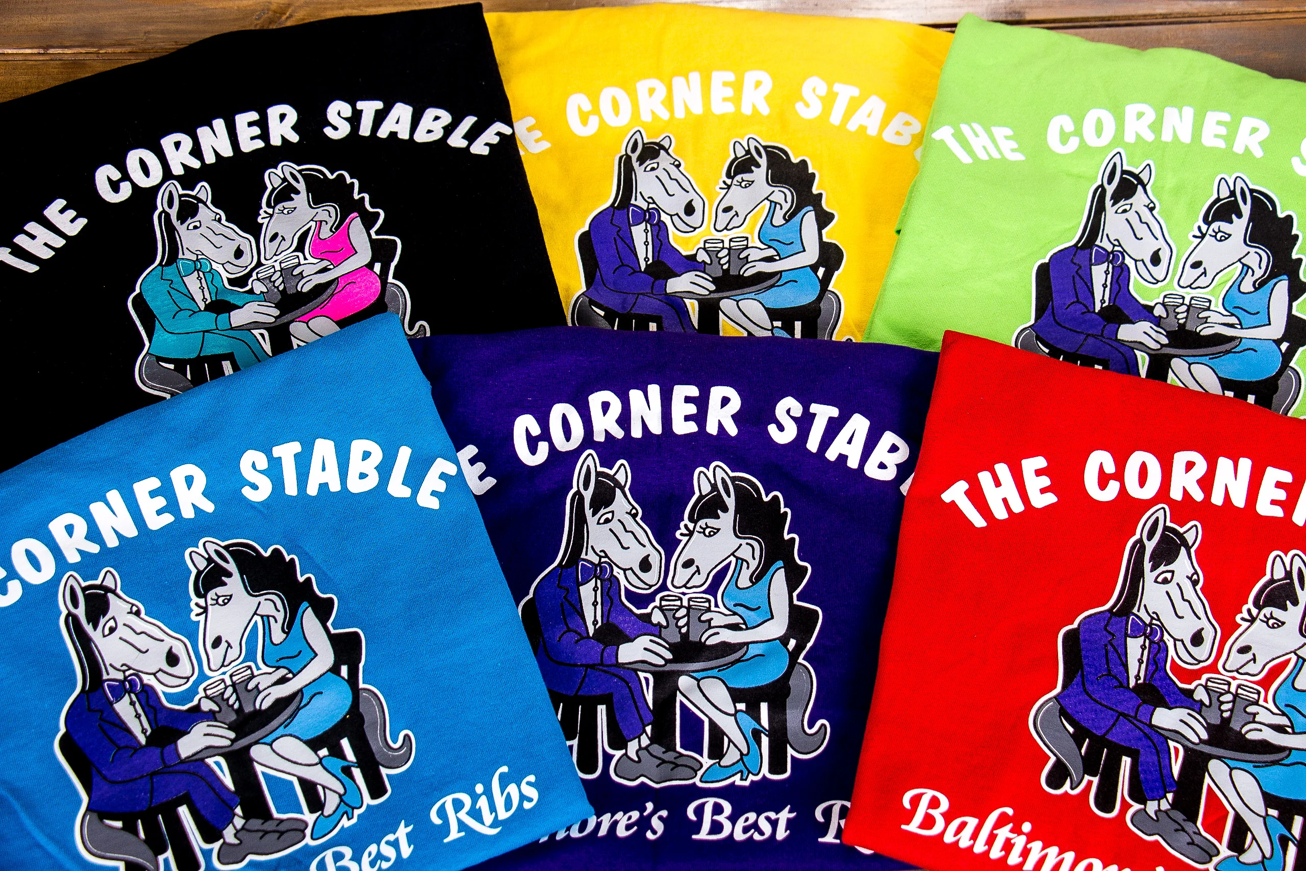 Colorful t-shirts featuring cartoon horses dining at a table