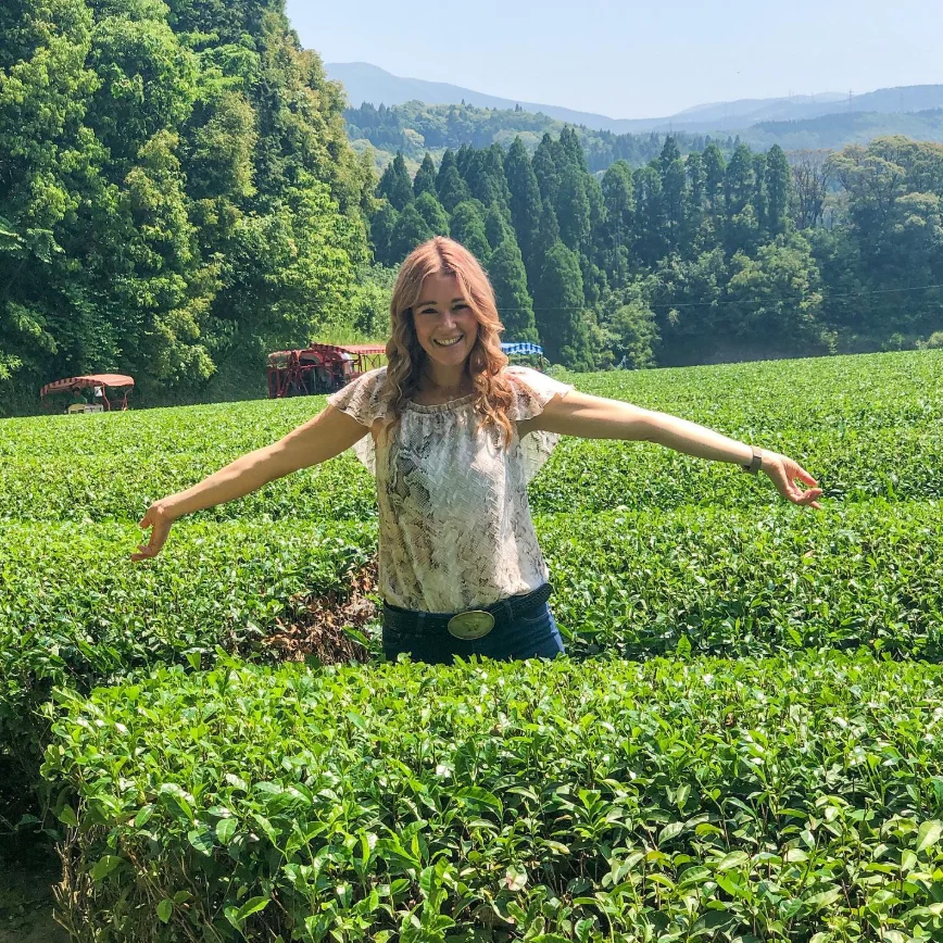 Person enjoying a tea plantation in lush green landscape
