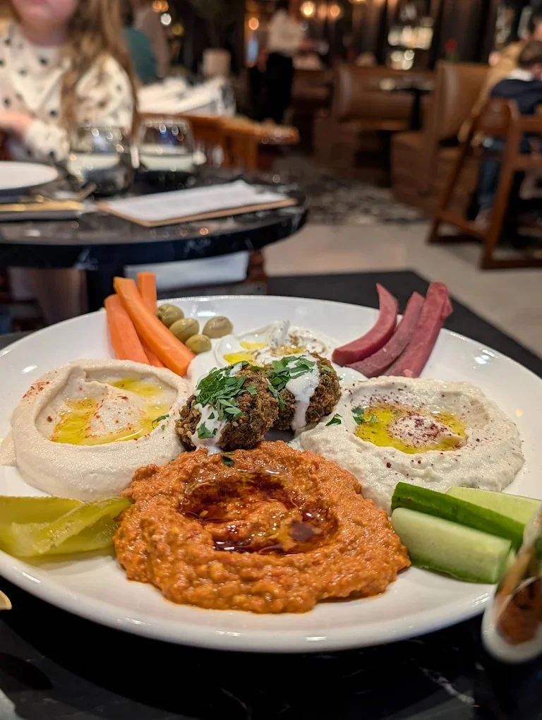 A colorful mezze platter featuring various dips and fresh vegetables.