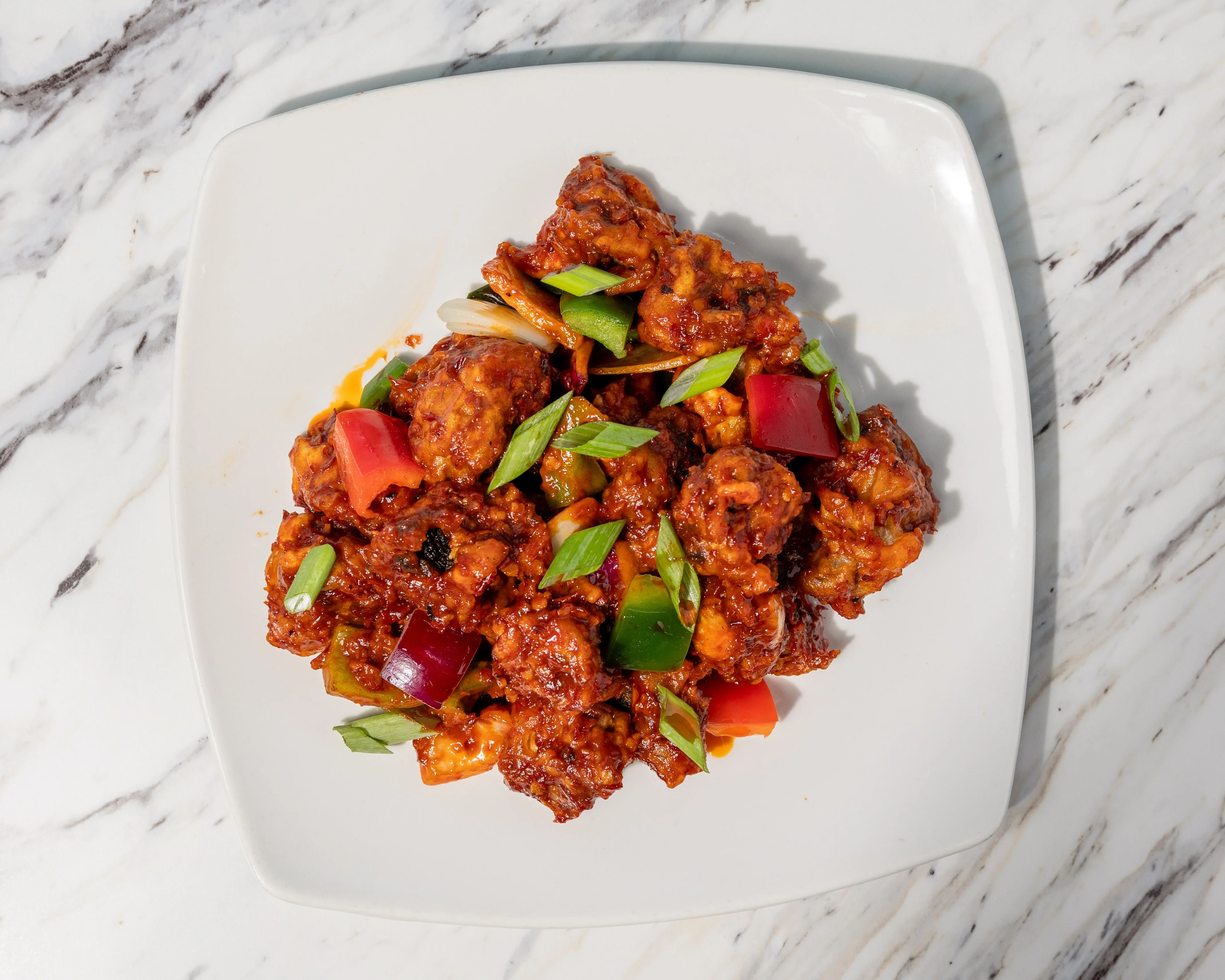 Spicy Indian chili chicken garnished with green onions