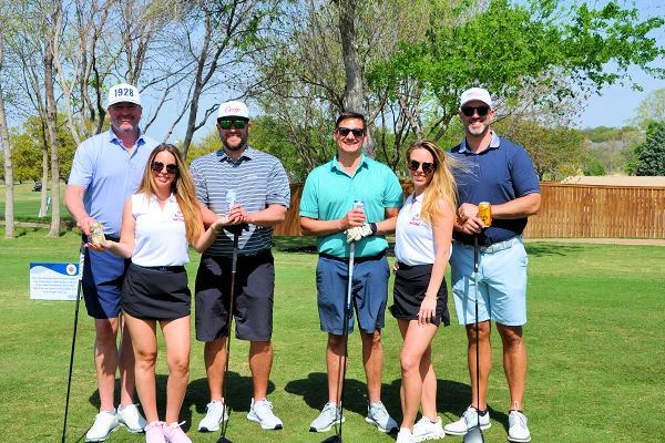 Group of golfers posing outdoors on a sunny course