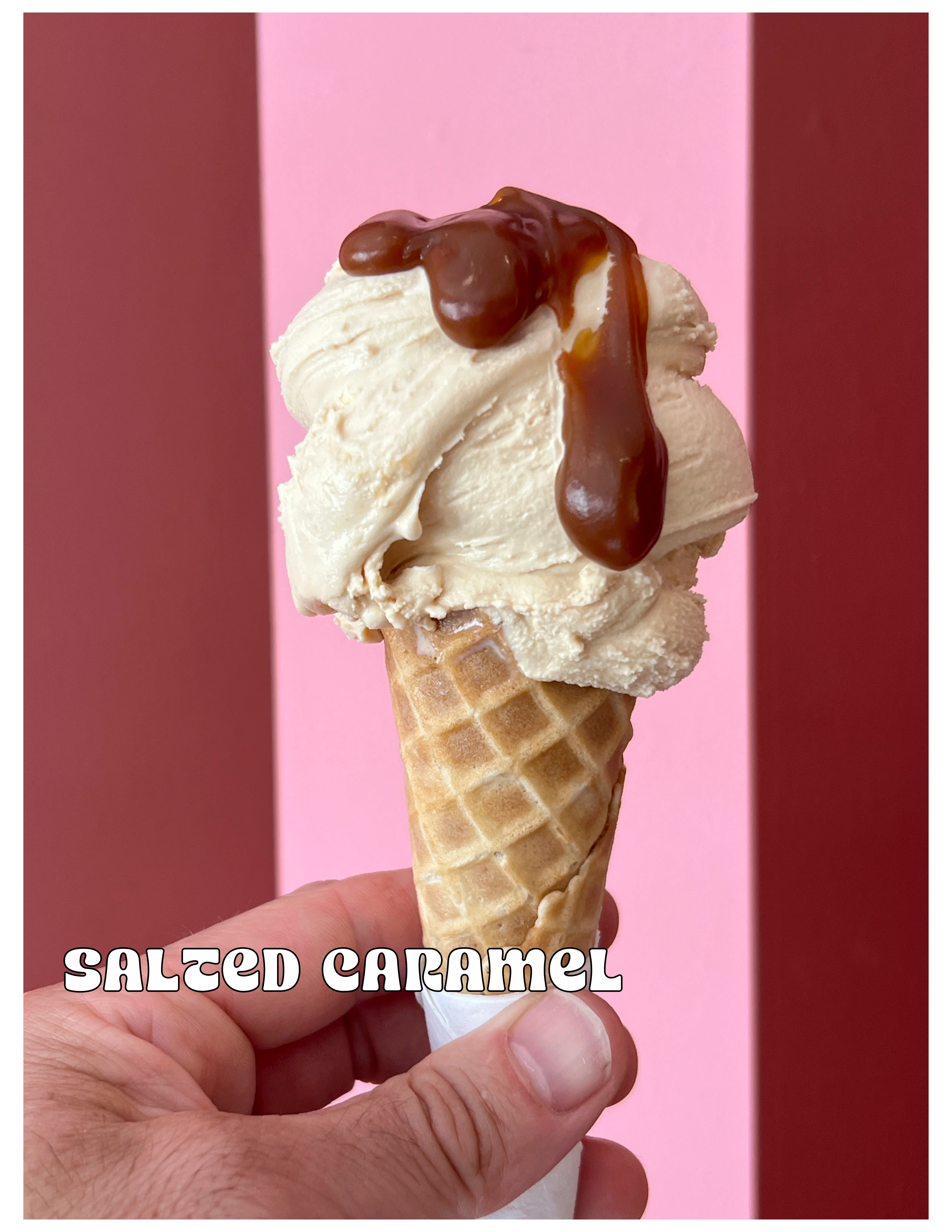 Delicious salted caramel ice cream cone against a pink background