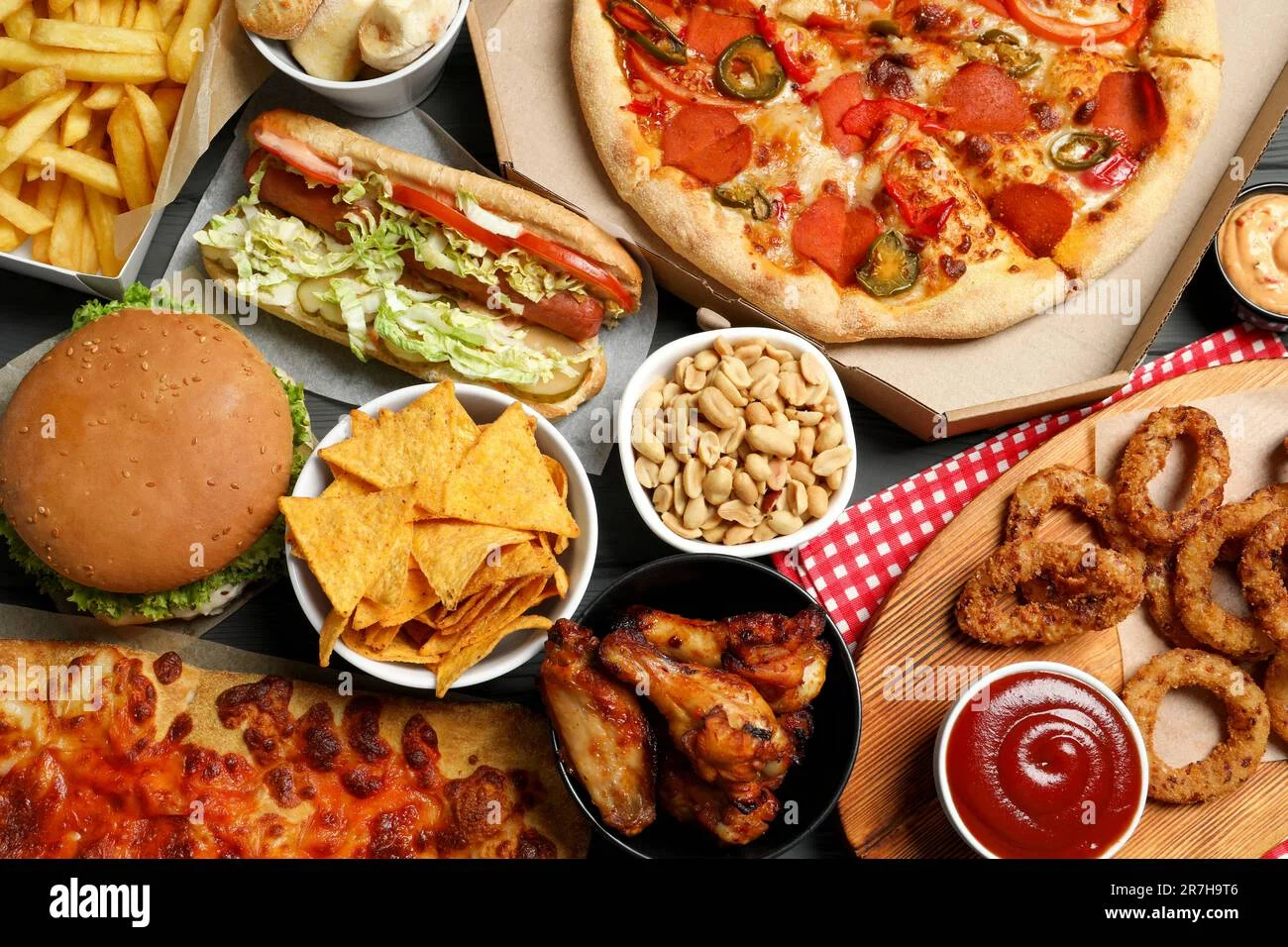 Top view of pizza, chips, and fast food on a table.