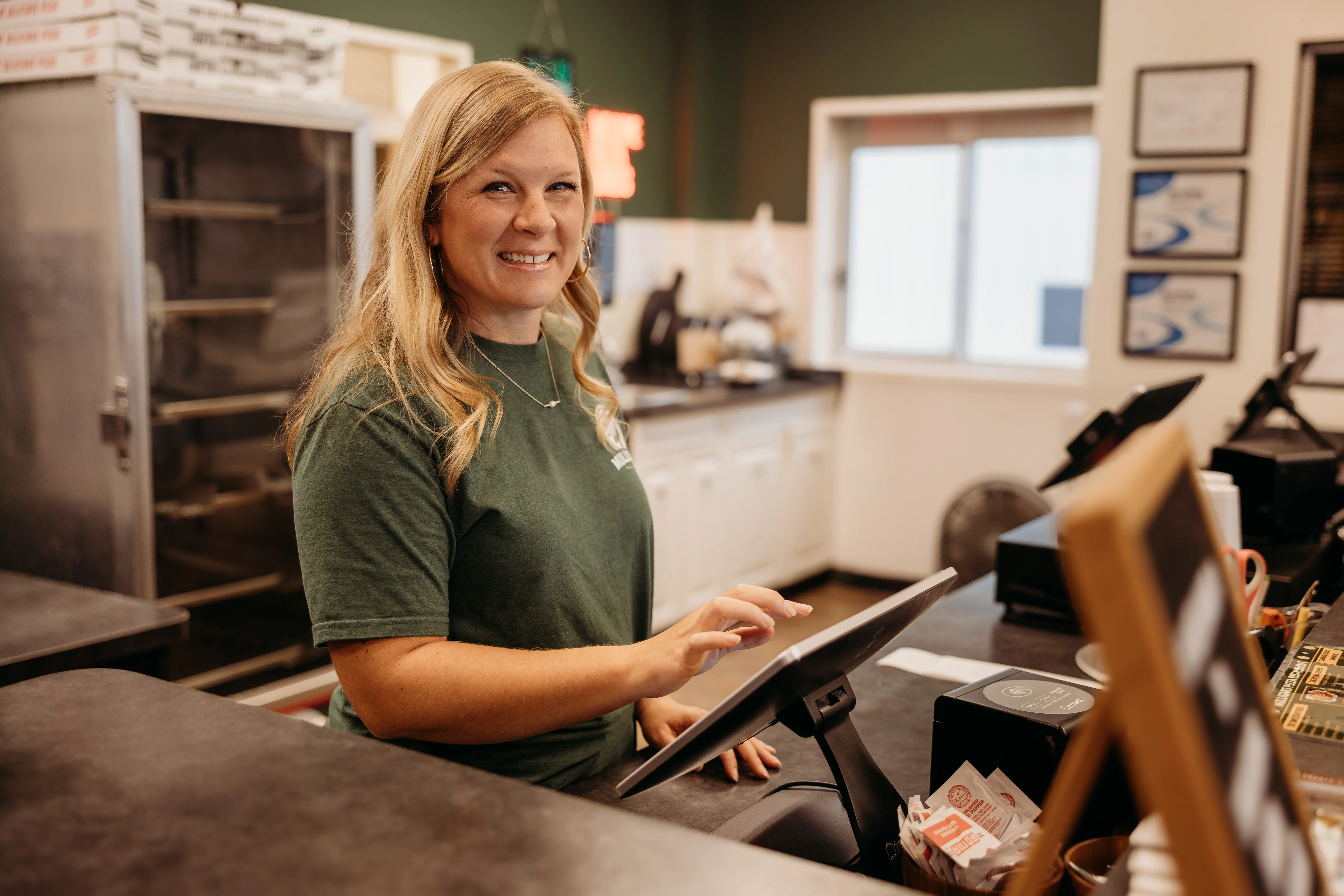 Friendly staff member at a restaurant counter with a digital ordering system