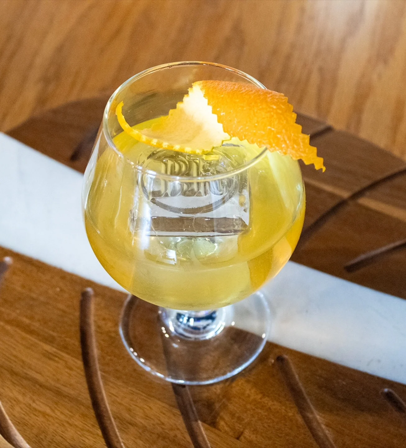 Craft cocktail served in a glass with orange twist garnish