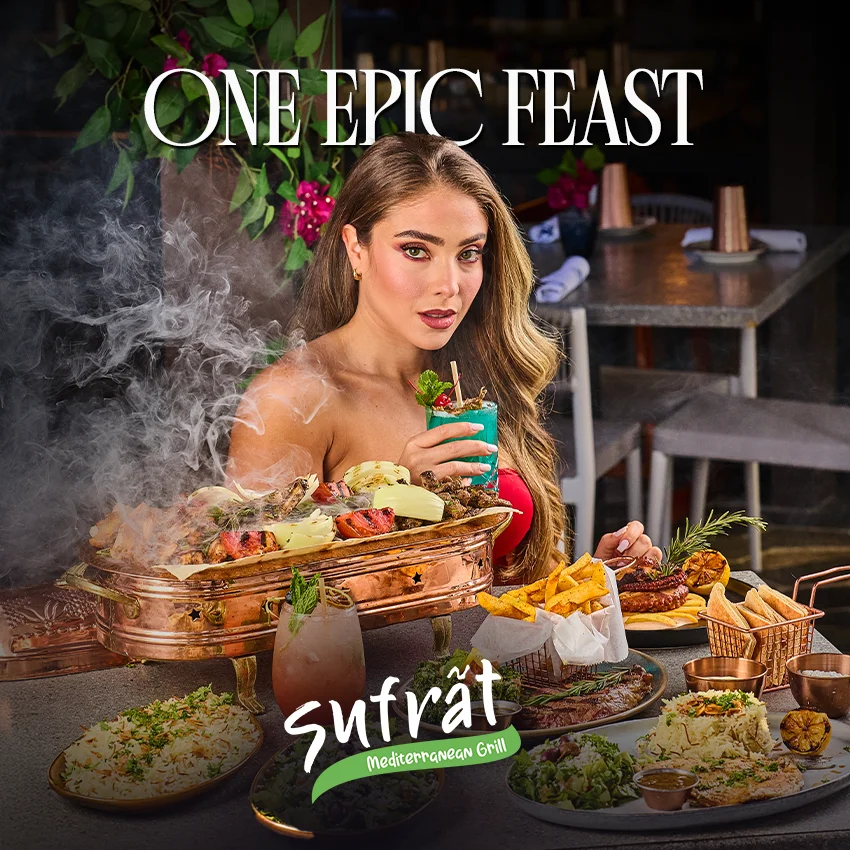 Woman dining at Sufrat Mediterranean Grill with a sizzling mixed grill platter, Mediterranean appetizers, cocktails, and more.