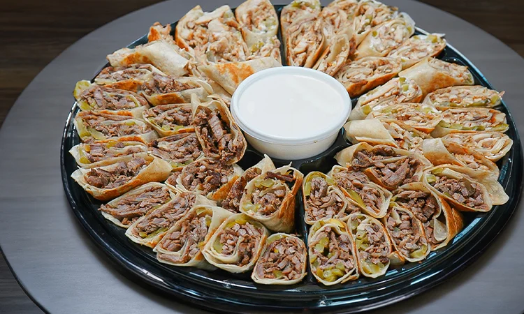 Platter of Middle Eastern shawarma wraps with dipping sauce