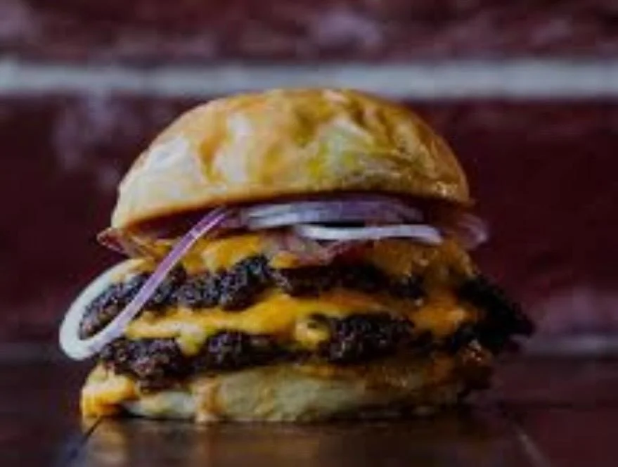 A stacked cheeseburger with layers of melted cheese, onions, and a soft bun.