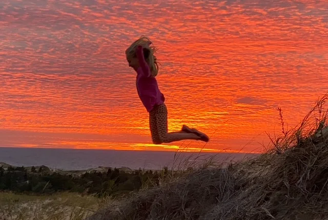 Child jumping against a vibrant sunset sky