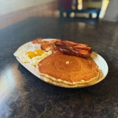 Classic American breakfast platter with pancakes, eggs, and bacon
