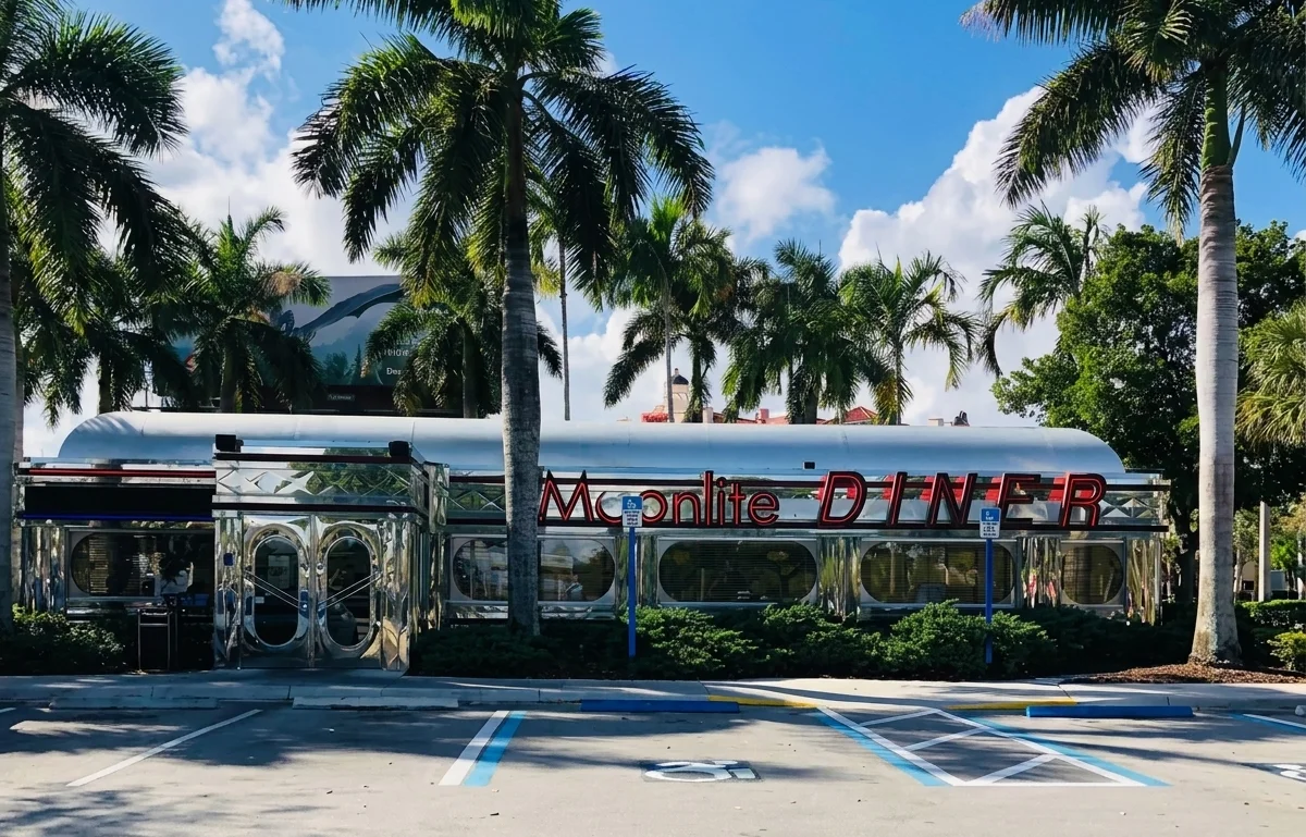 Front entrance of Moonlite Diner welcoming guests to a classic retro American diner surrounded by palm trees