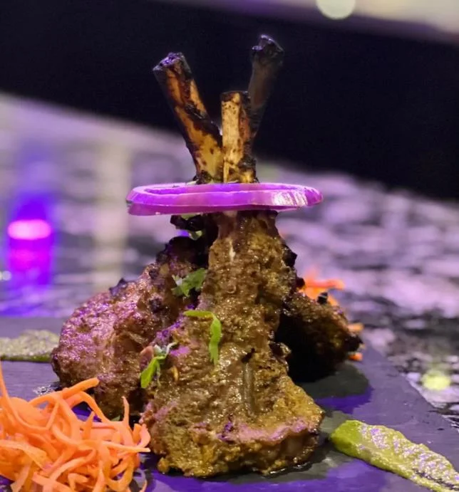 Grilled lamb chops with spices, served on a black slate platter