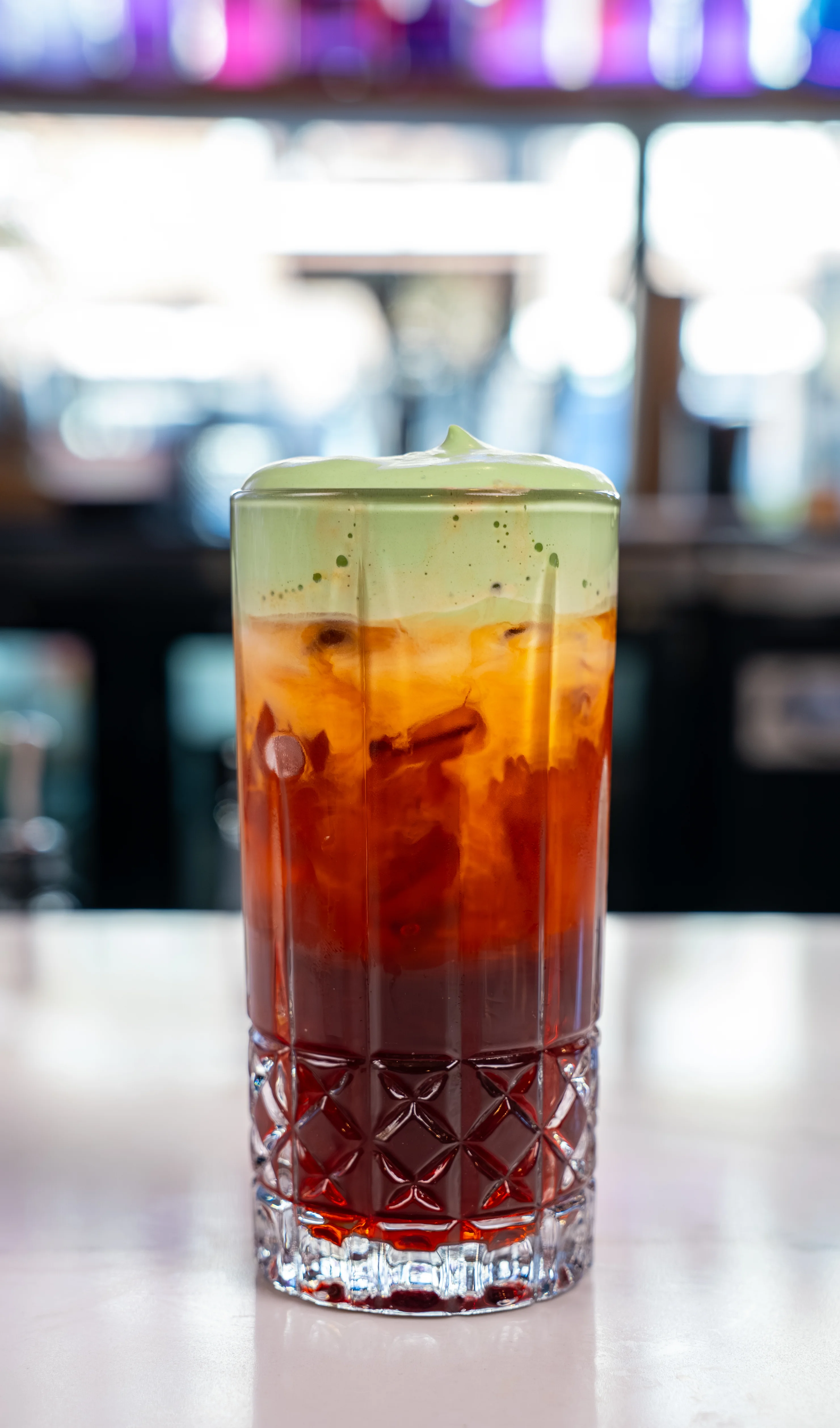 Colorful mocktail served in a glass with garnishes on a wooden table.