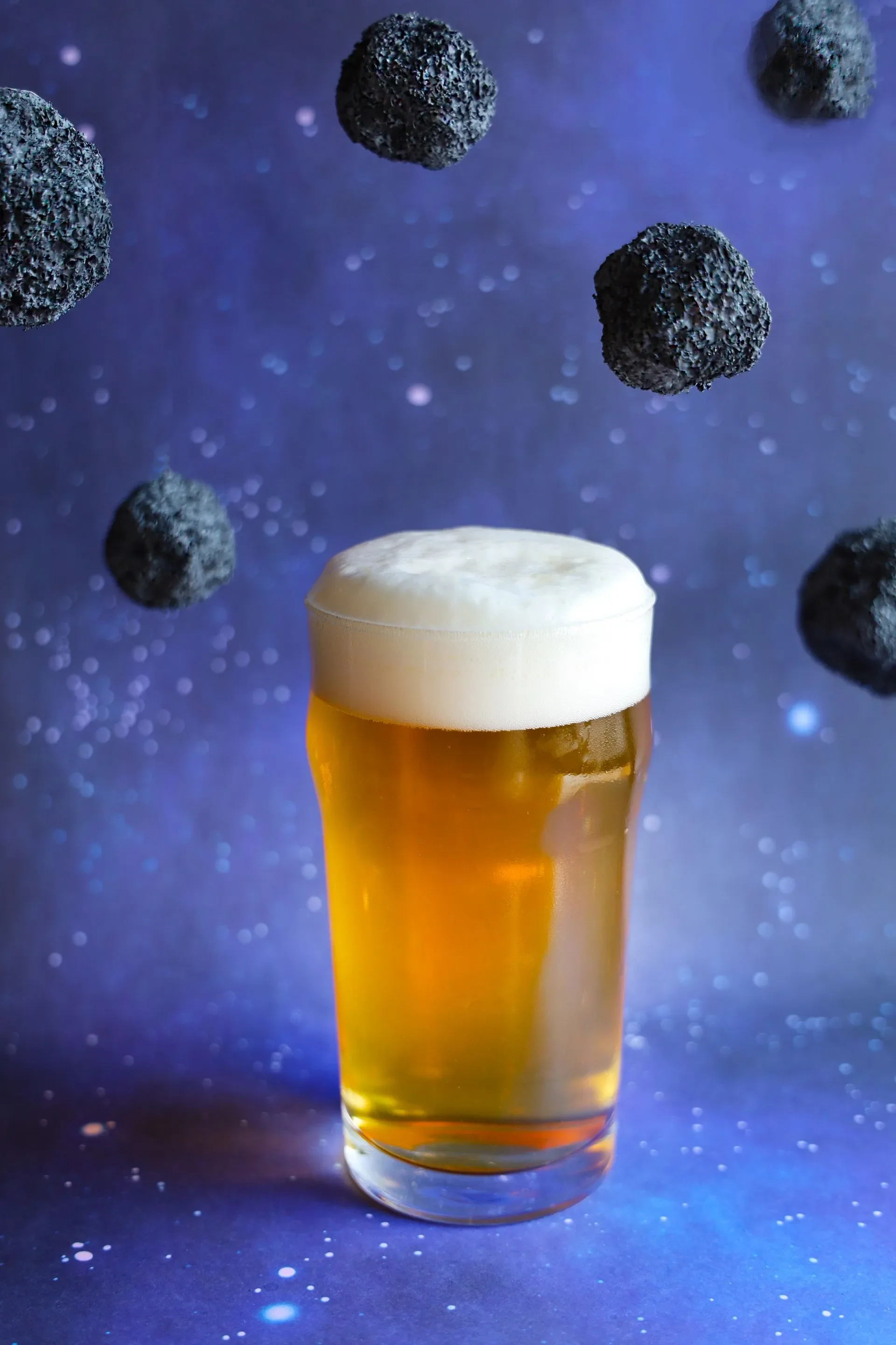 Glass of beer with cosmic background and floating rocks