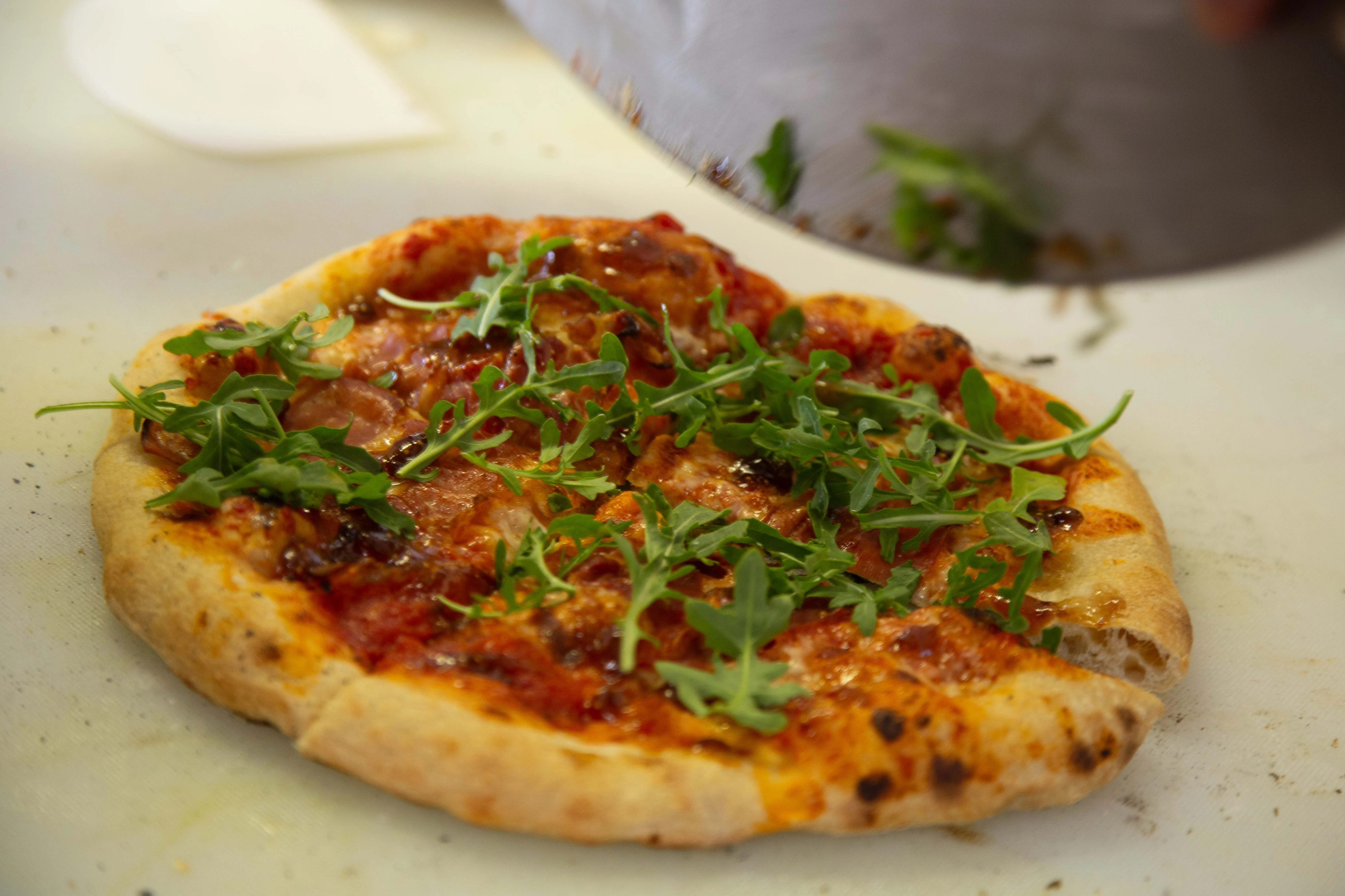 Freshly made pizza topped with arugula