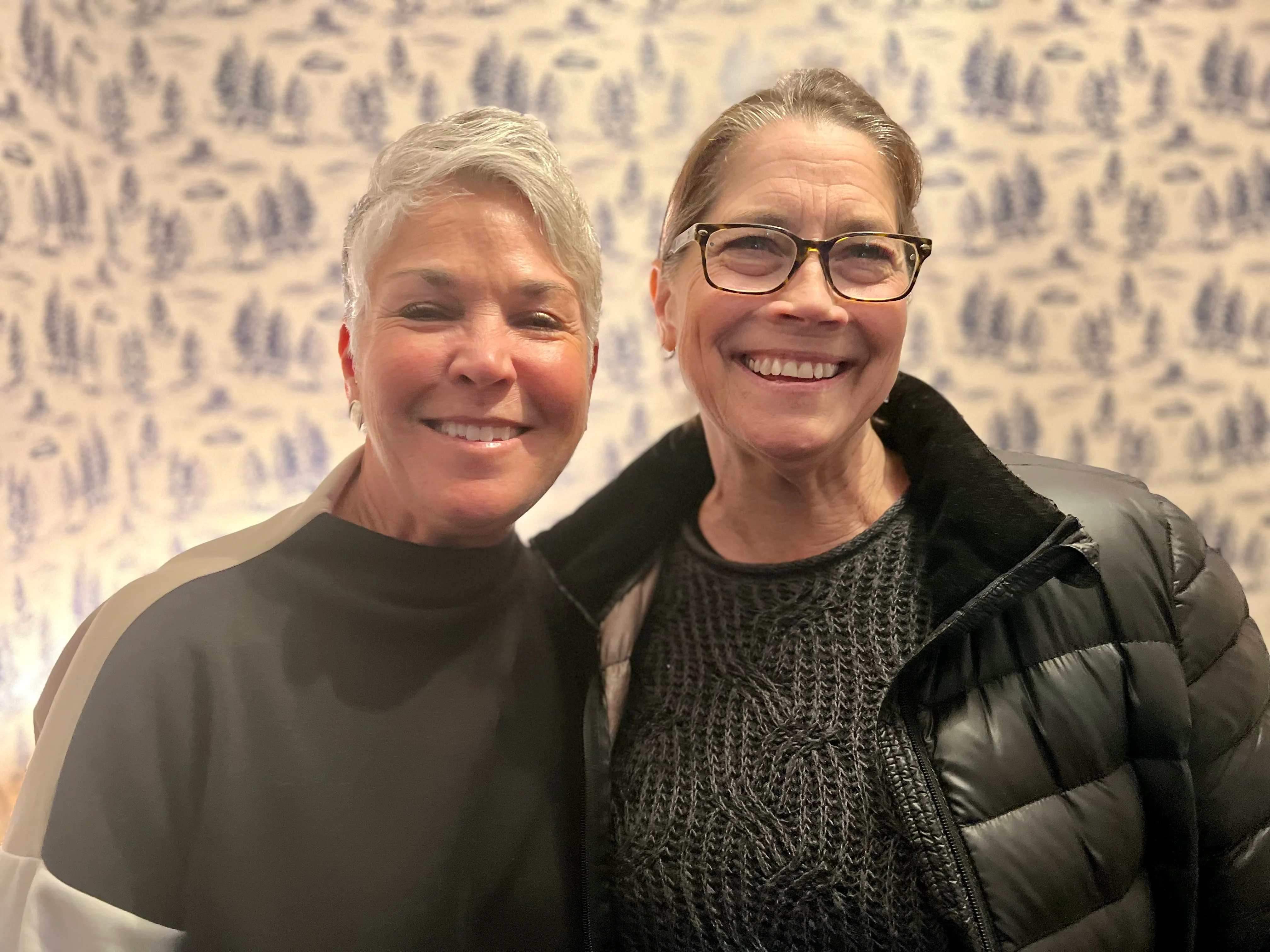 Two smiling women posing together in a cozy setting