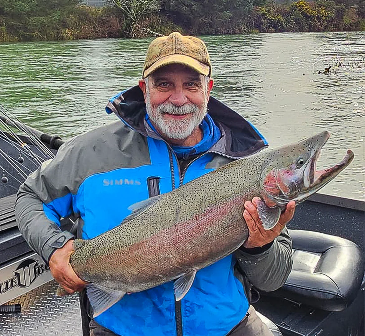Angler proudly holding a large rainbow trout by the river