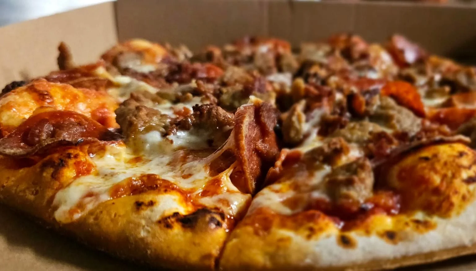 Delicious pepperoni and sausage pizza in a takeout box