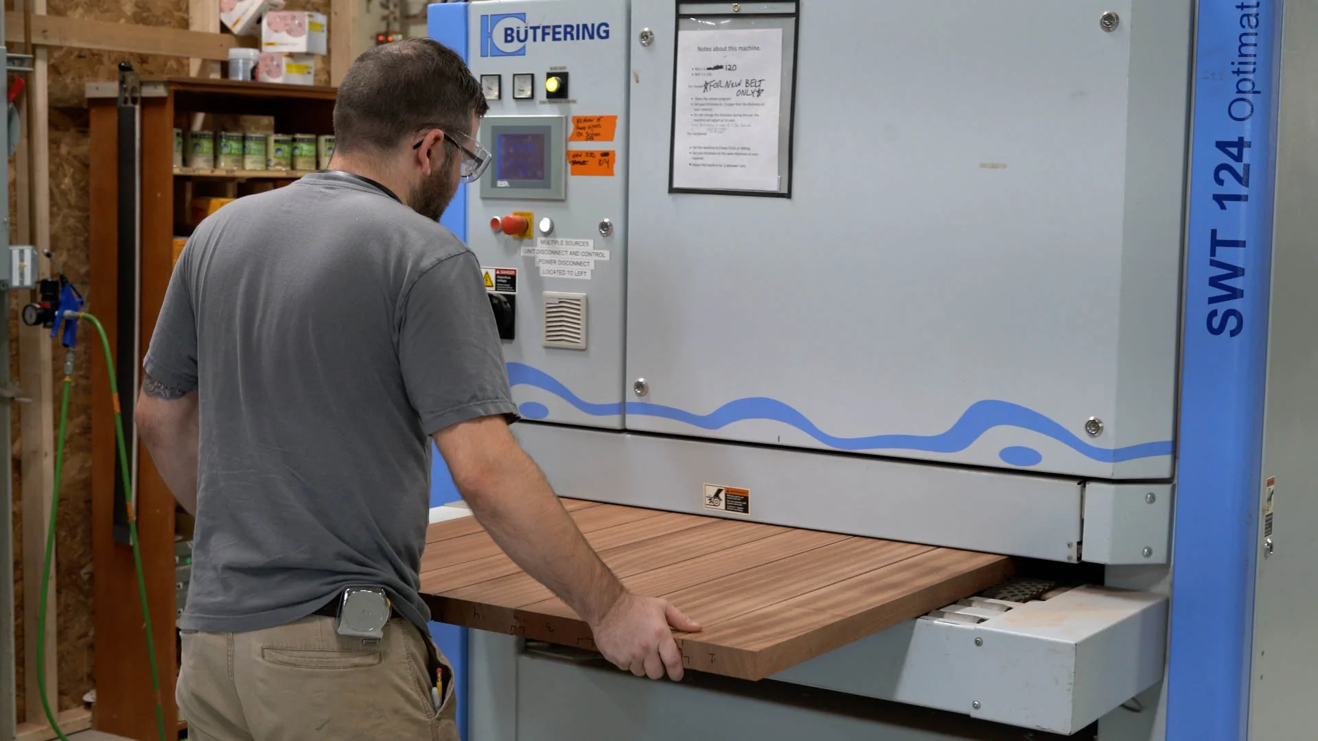 Worker operating a wood sanding machine in a workshop