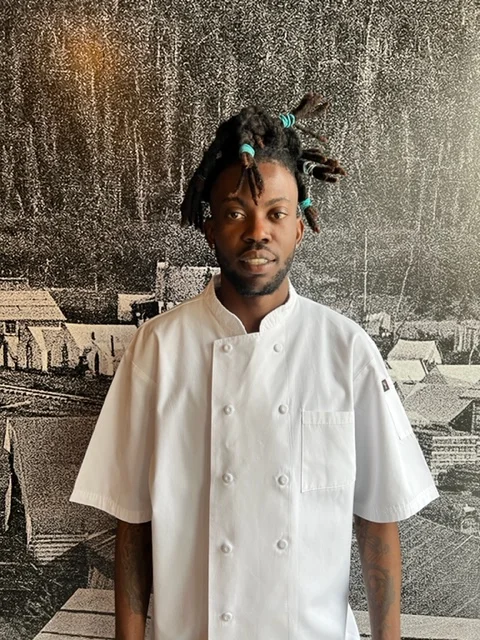Chef in a white uniform against a textured backdrop