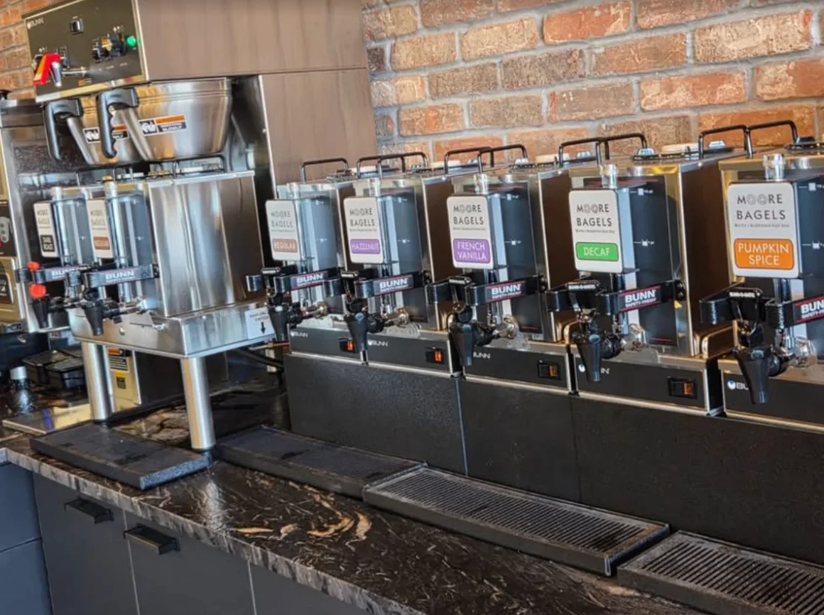 A coffee station showcasing various coffee dispensers labeled with different flavors and a brewing machine.