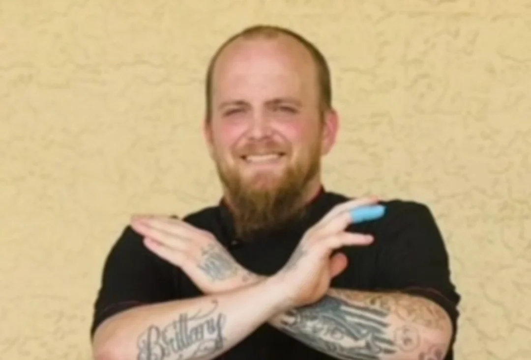 Chef posing confidently with crossed arms and tattoos