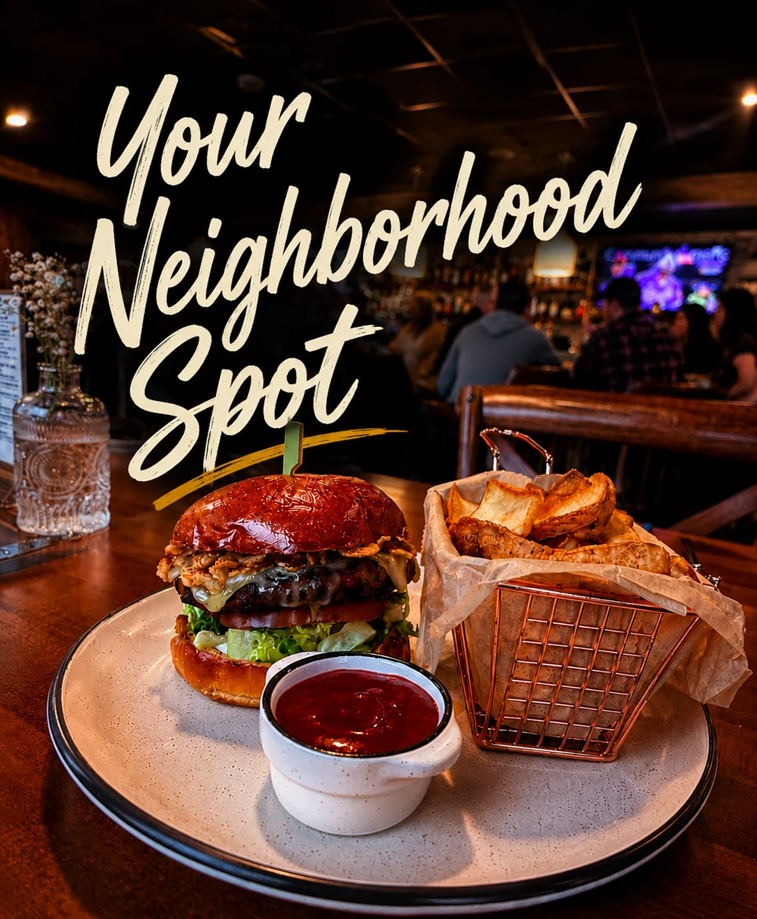 A delicious burger with fries and dipping sauce on a wooden table.