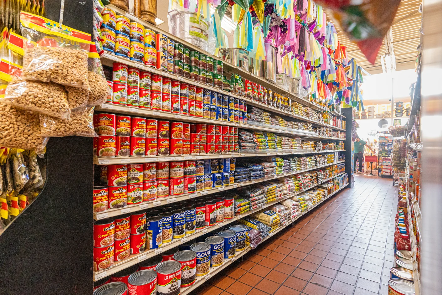 Aisle of a vibrant Latin grocery store filled with canned goods and colorful decorations