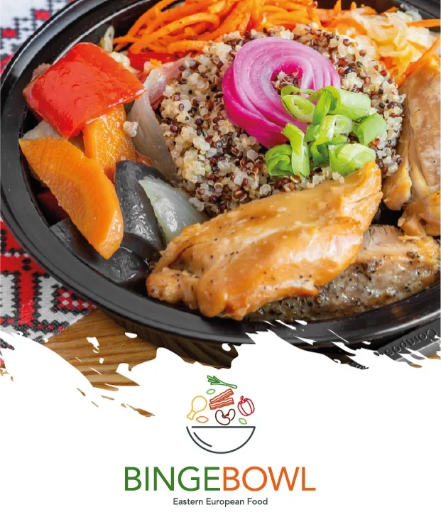 A vibrant bowl featuring quinoa topped with grilled chicken, colorful vegetables, and garnished with sliced onions and green onions.