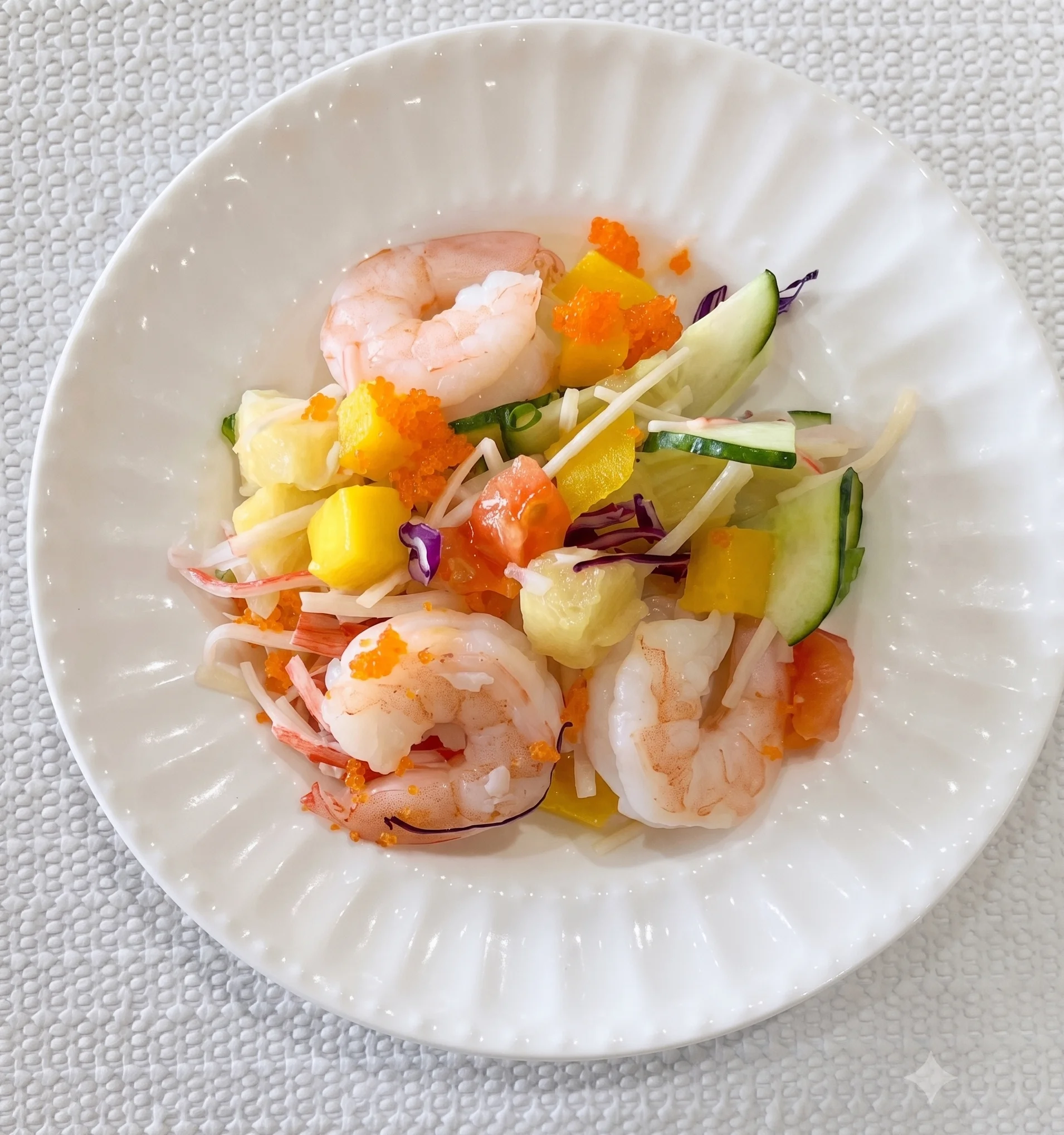Shrimp salad with mango, cucumber, and colorful garnishes on a white plate.