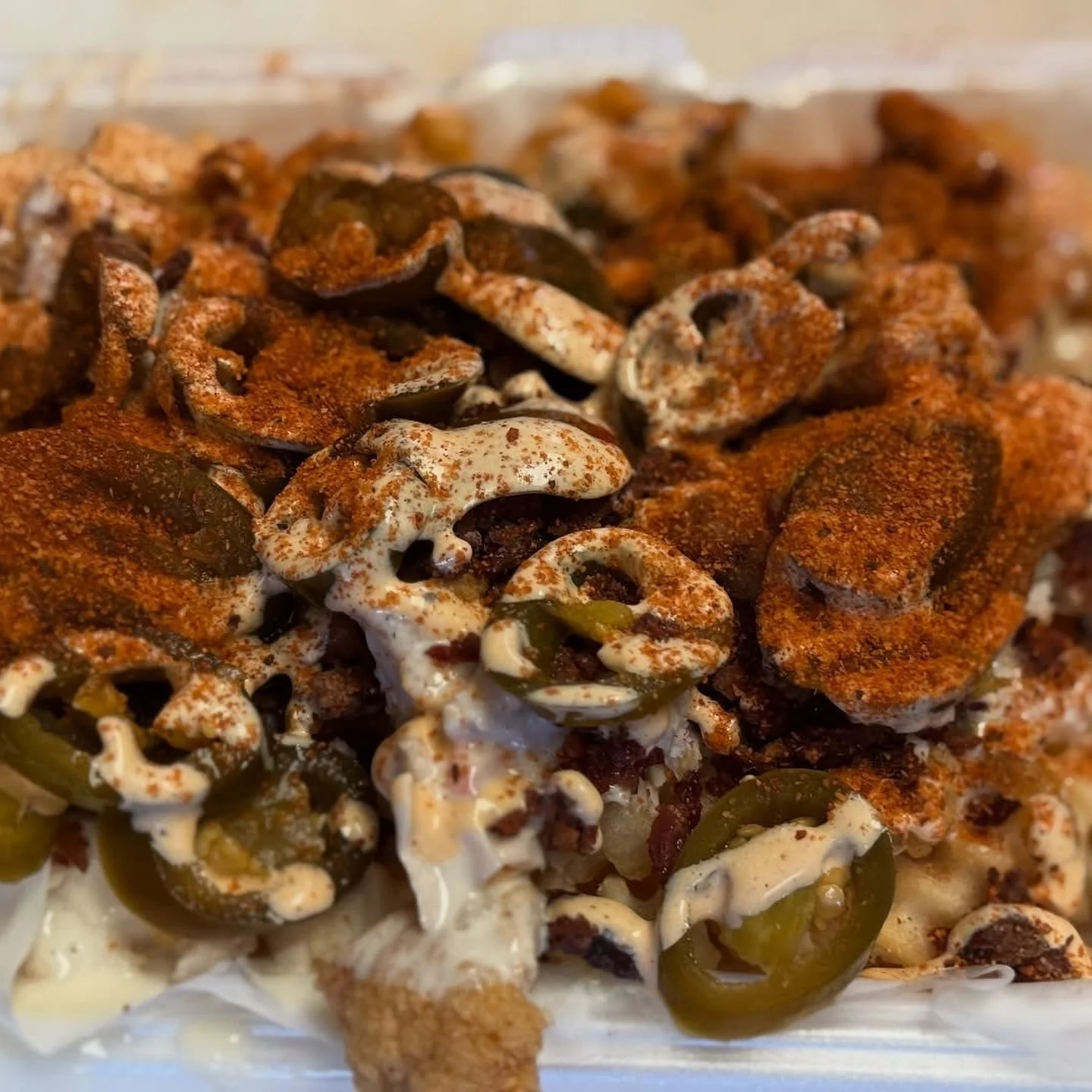 Loaded nachos topped with jalapeños, spices, and creamy sauce.