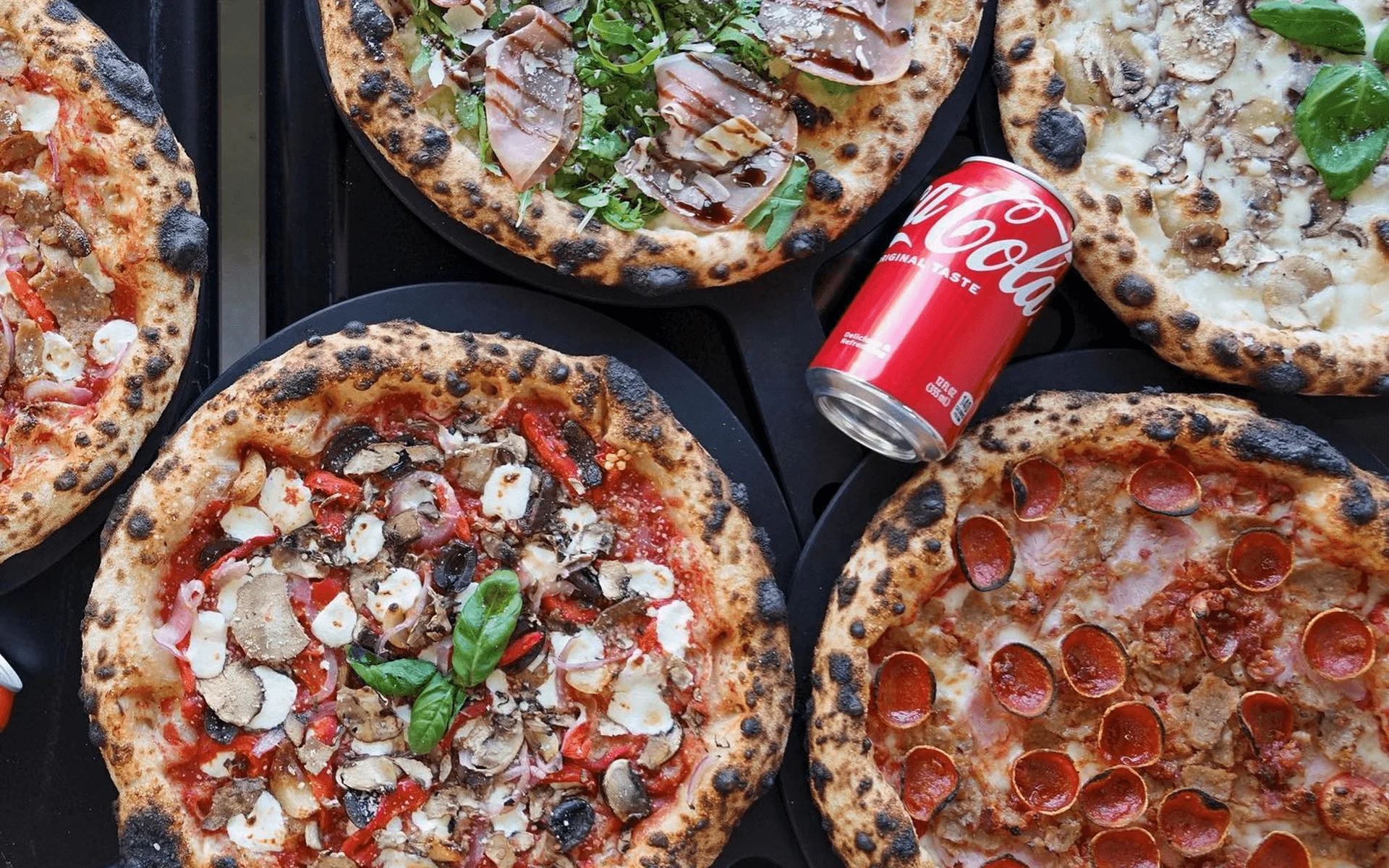 Assorted Neapolitan pizzas with a can of cola