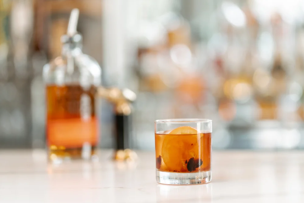 Close up of a crafted cocktail in a rocks glass on a marble bar