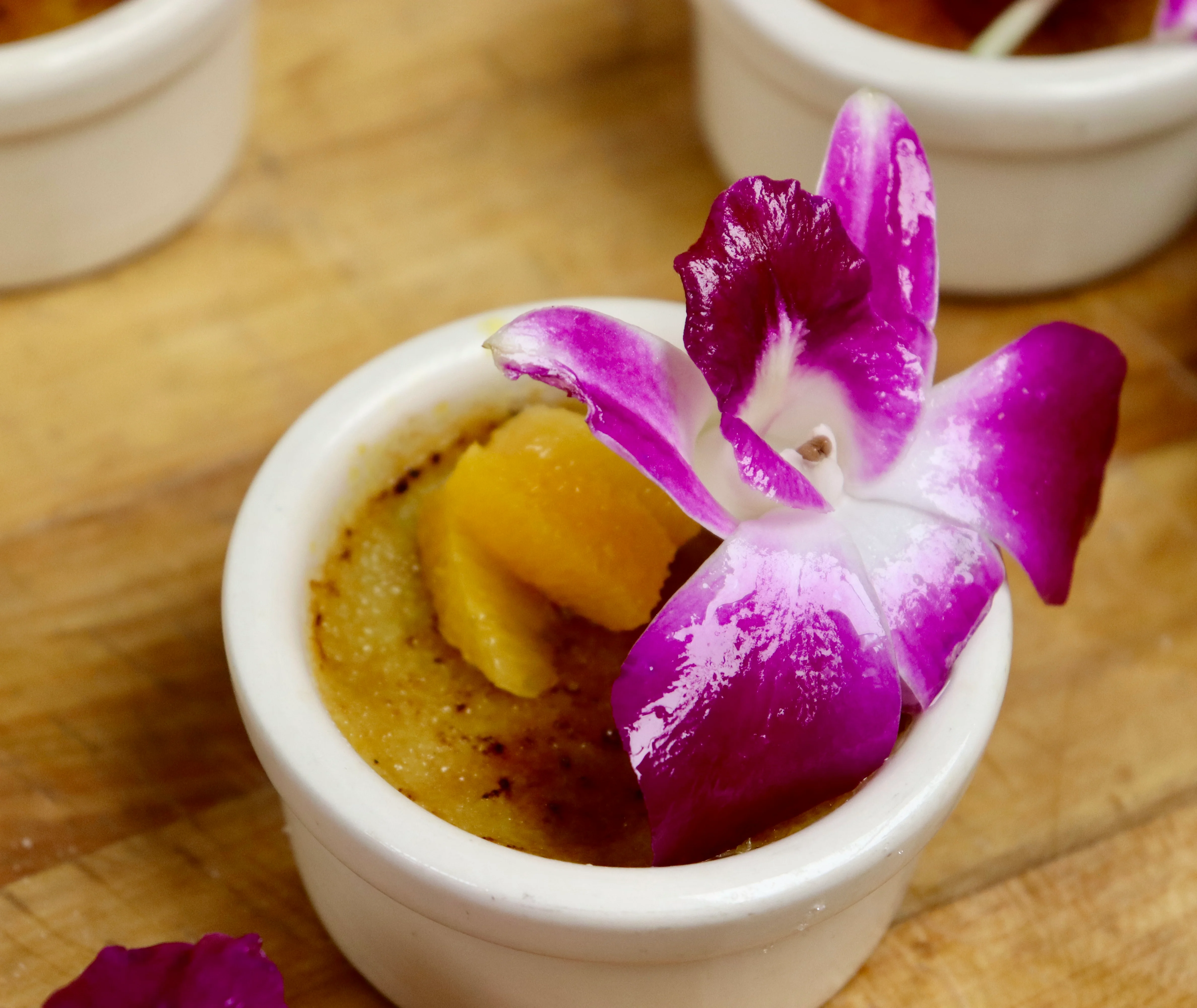Delicate crème brûlée topped with a vibrant orchid flower