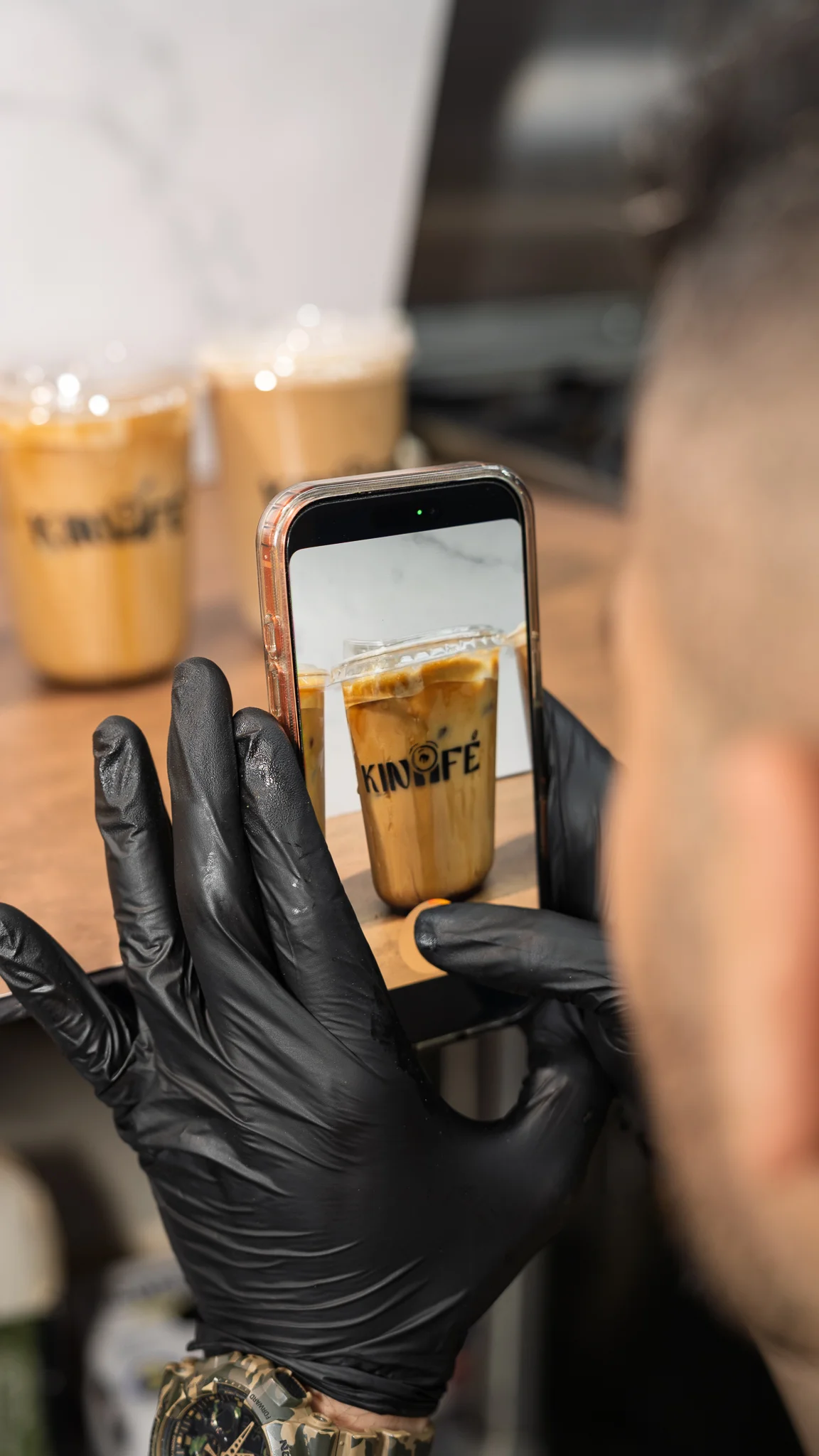 A person taking a photo of iced coffee drinks with a smartphone.
