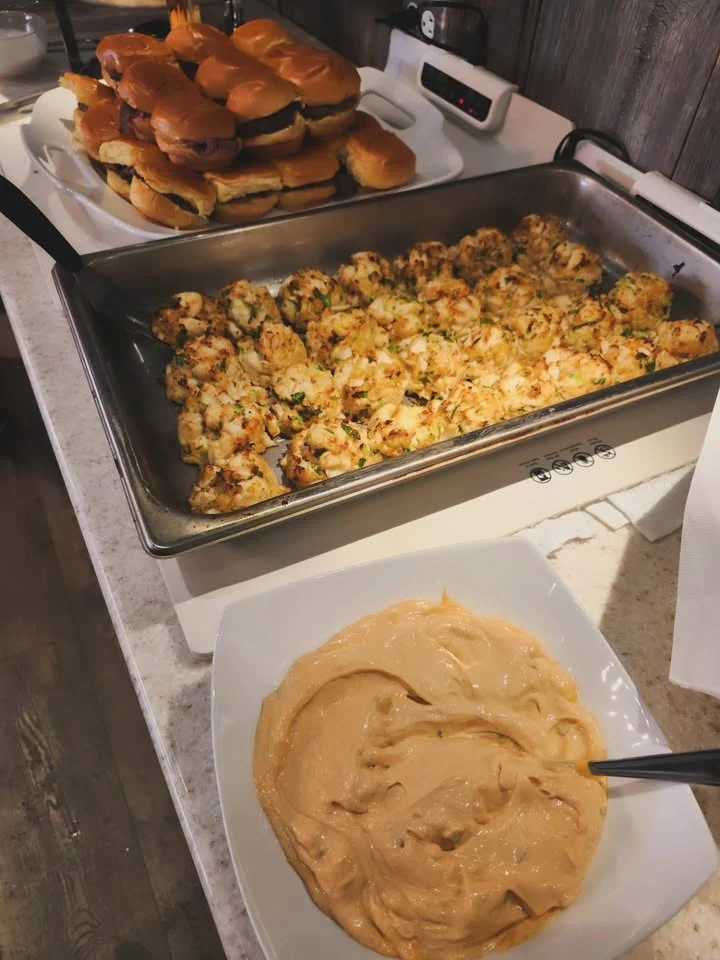Savory crab cakes with dipping sauce and sliders on a buffet table