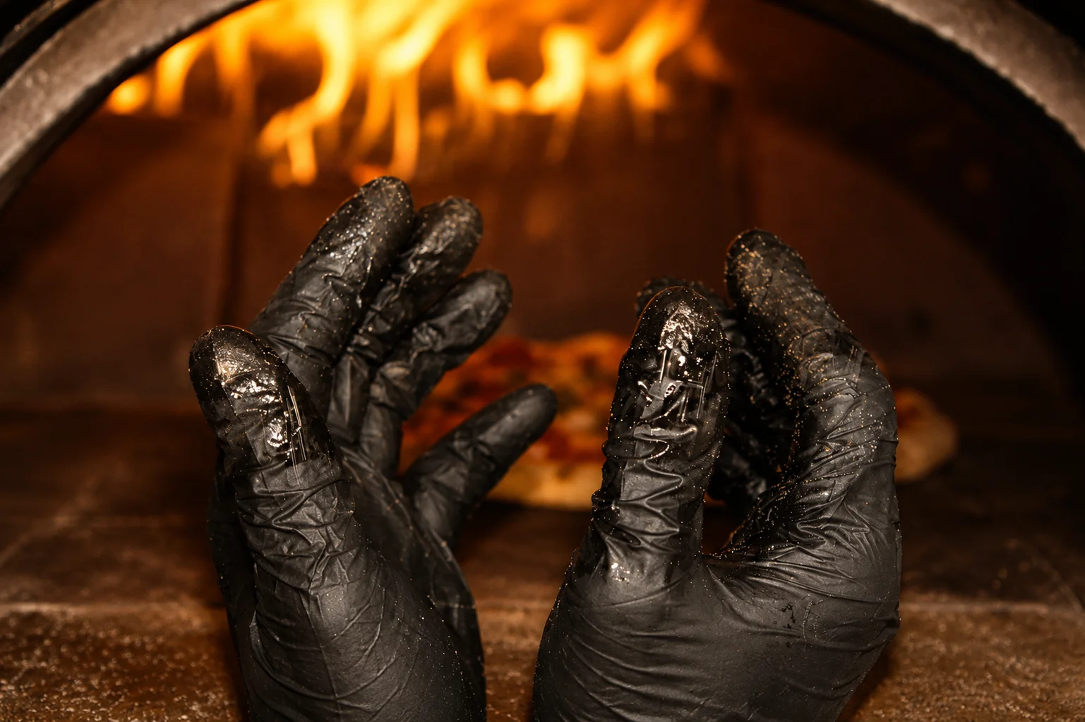 Chef's hands preparing Margherita pizza in a wood-fired oven