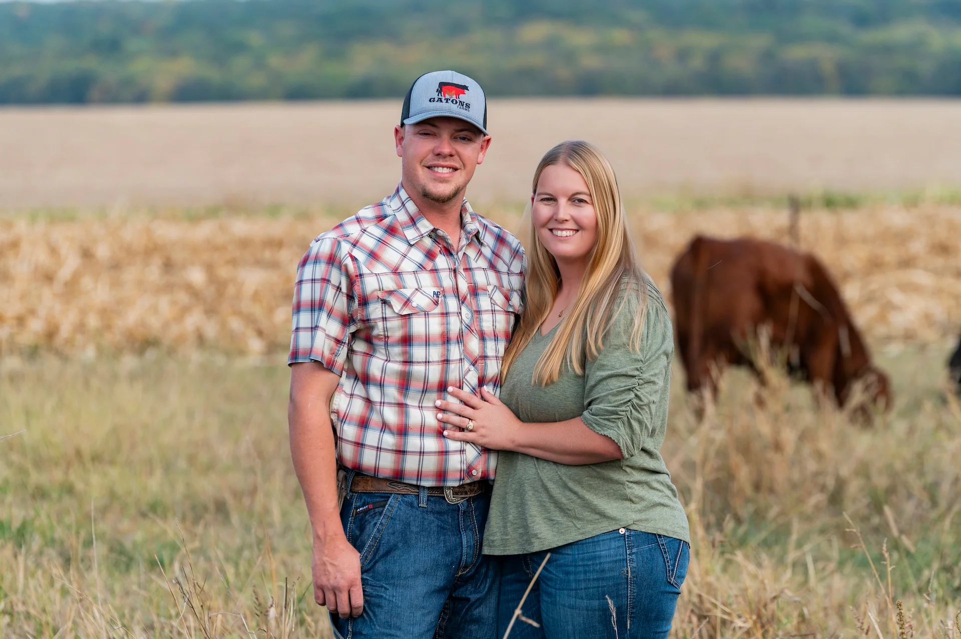 Couple posing in a field with cattle in the background