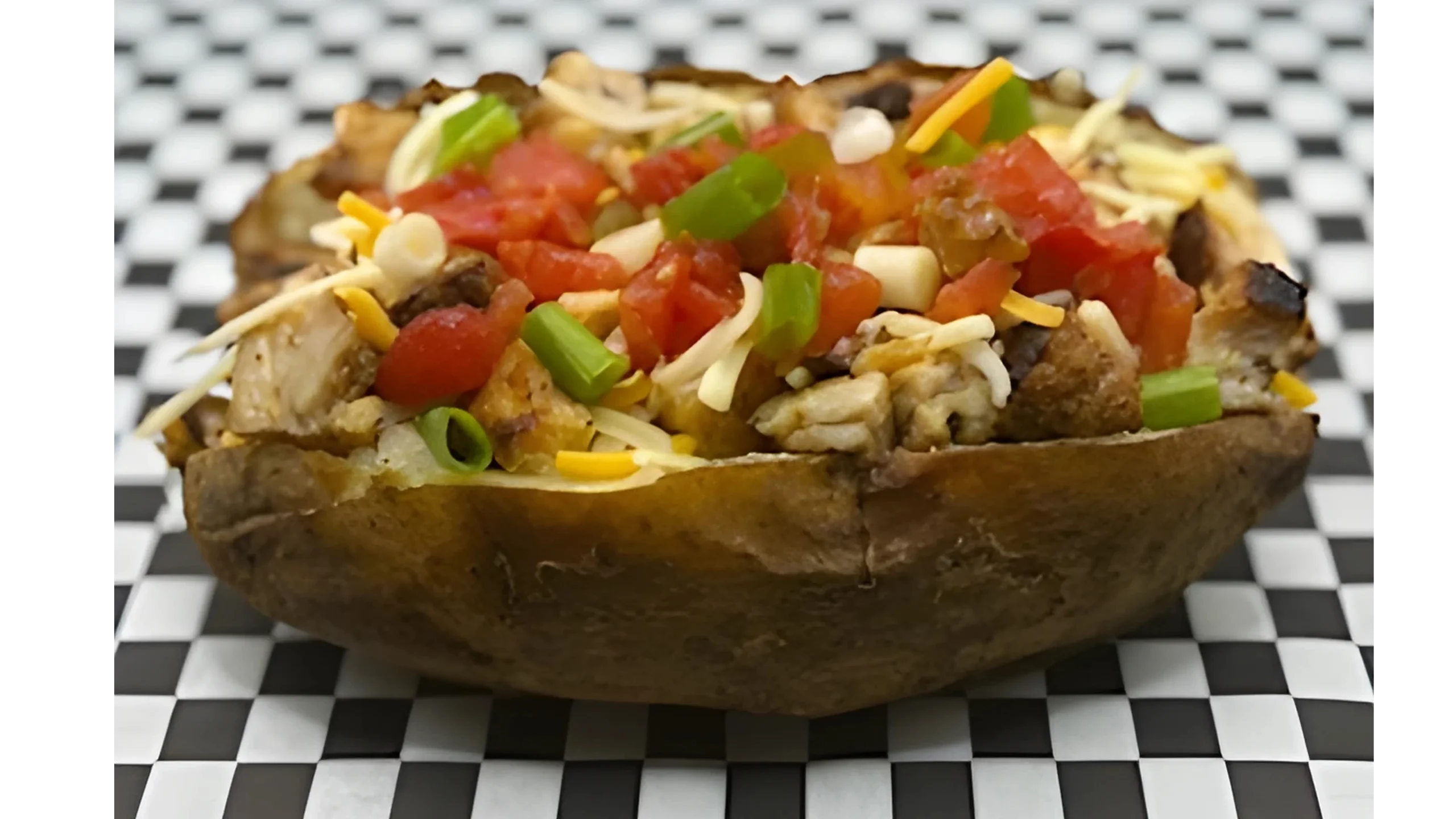 A loaded baked potato with tomatoes and chives