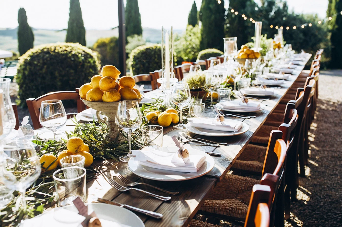 Elegant outdoor restaurant table set with lemons and string lights