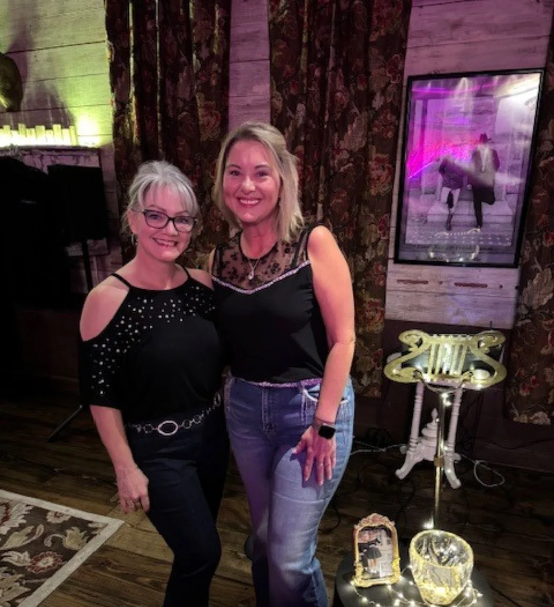 Two women posing at a stylish event with elegant decor