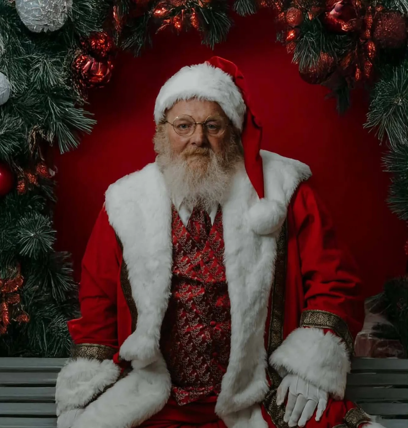 Santa Claus in festive attire sitting in a decorated holiday setting