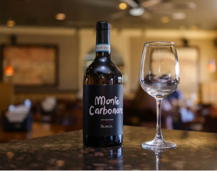 Bottle of Monte Carbonare wine with a glass in a restaurant setting