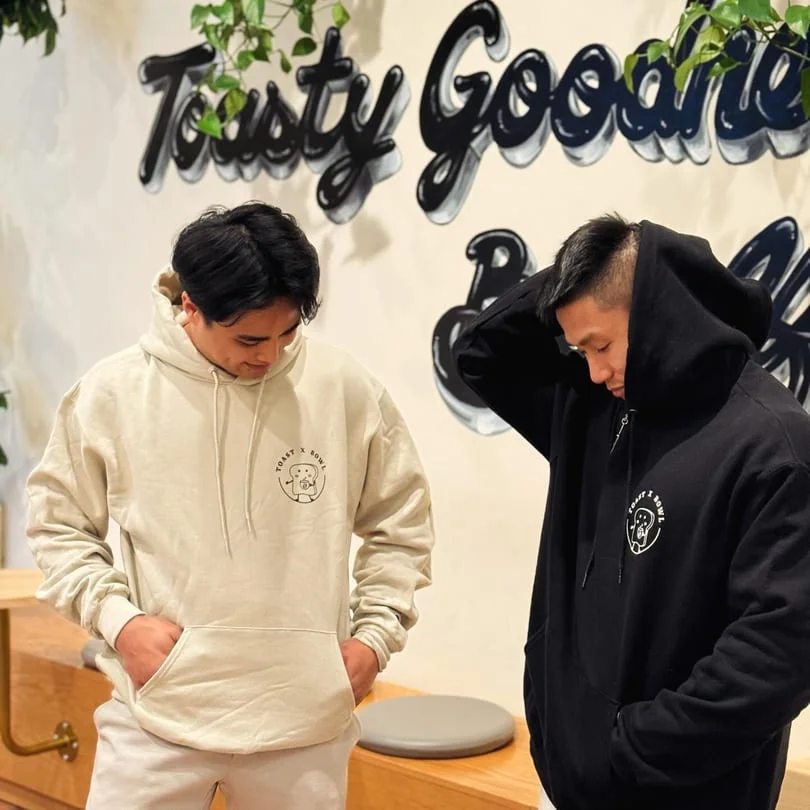 Two friends wearing stylish hoodies in a cozy cafe setting