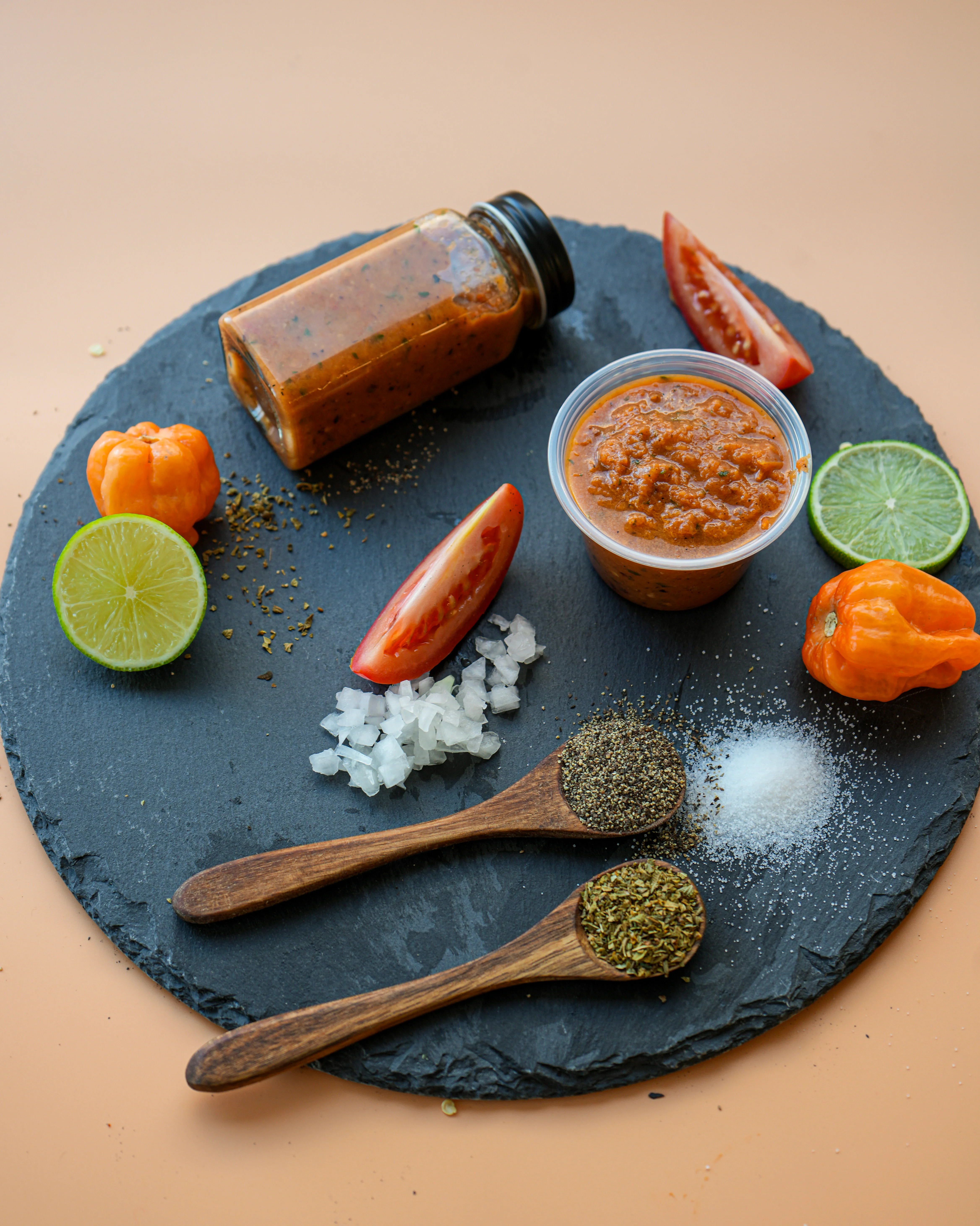 A collection of condiments and ingredients on a slate board, including sauces, fresh vegetables, and spices.