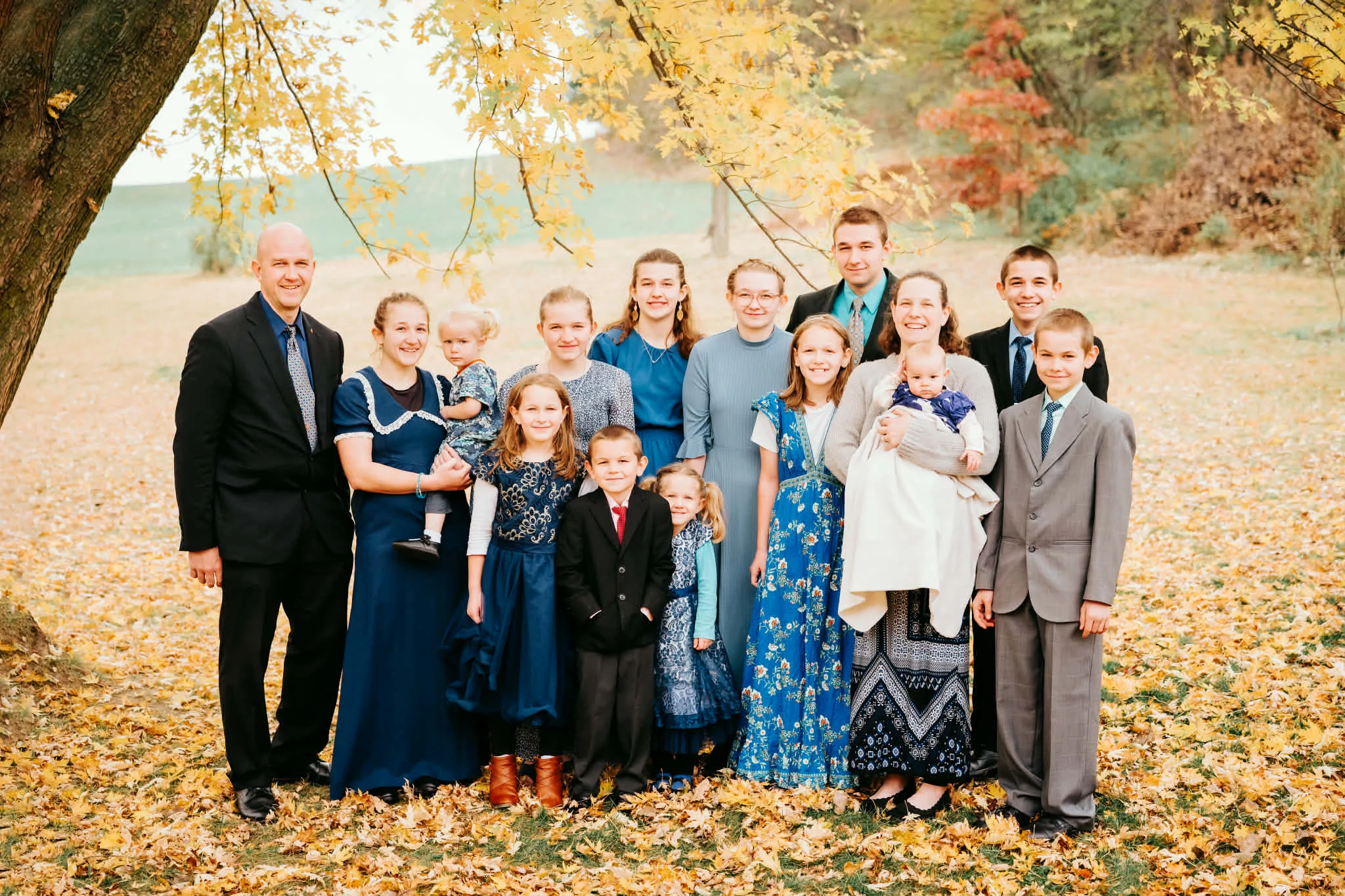 Curtis and Vickie Eberle with their 13 children with yellow fallen leaves.