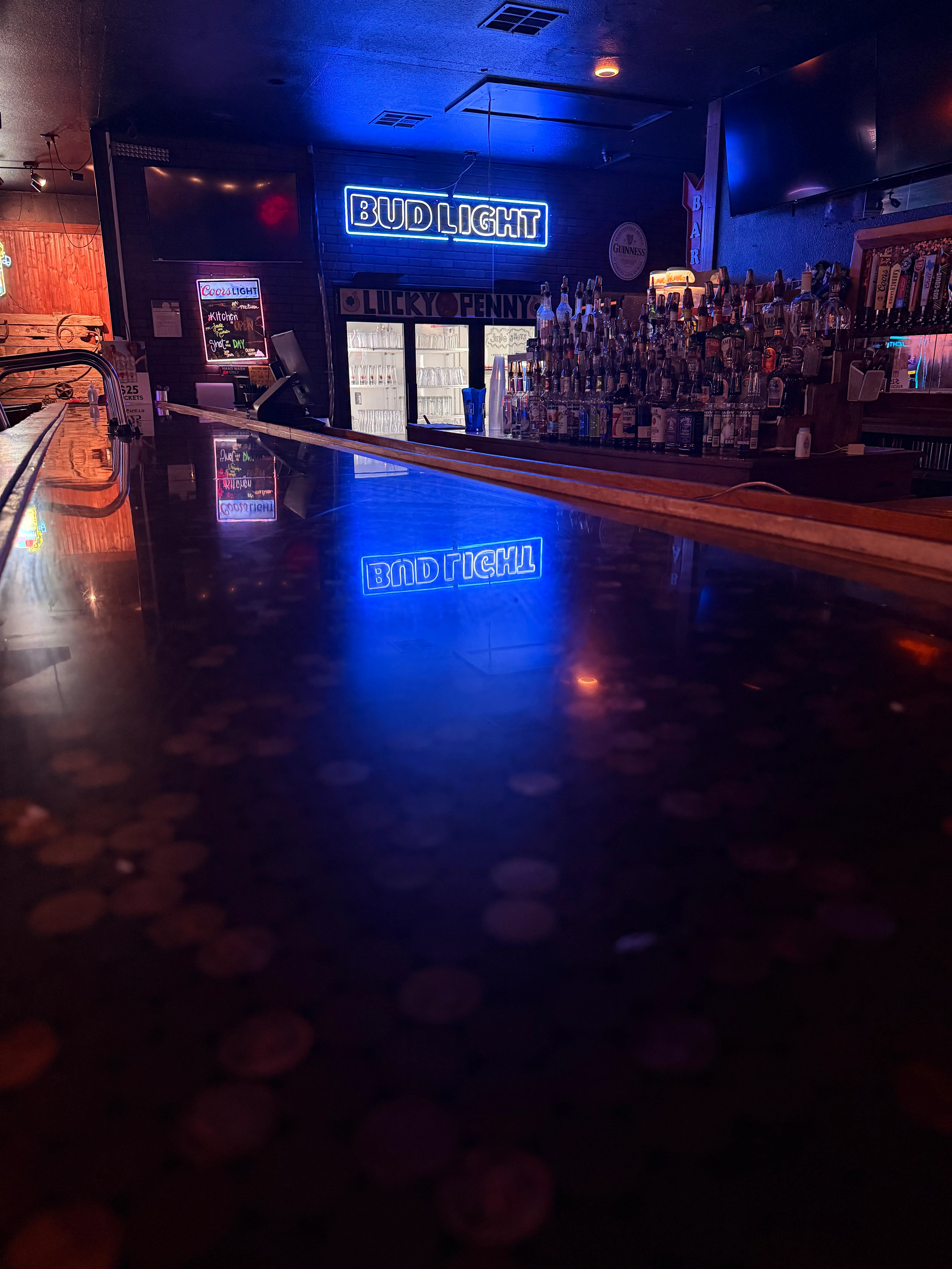 Bar counter with illuminated signage and a variety of liquor bottles