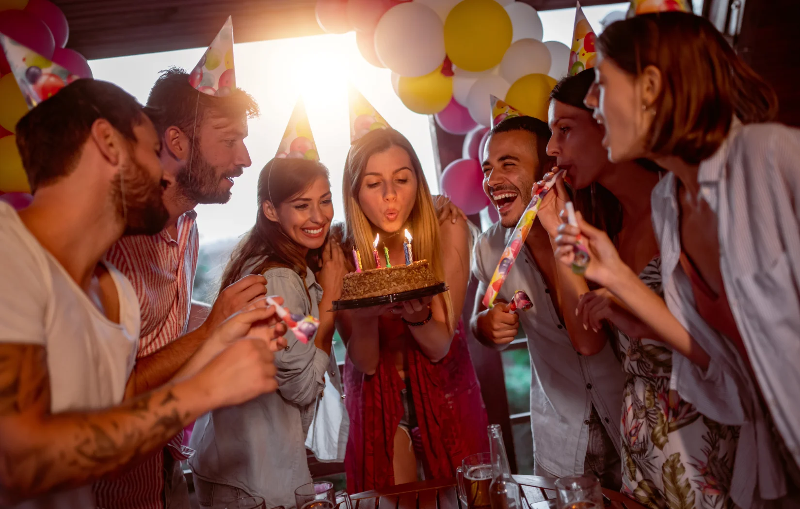 Group celebrating a birthday with cake and party hats